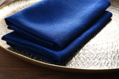 Photo of Tray with blue kitchen napkins on wooden table, closeup