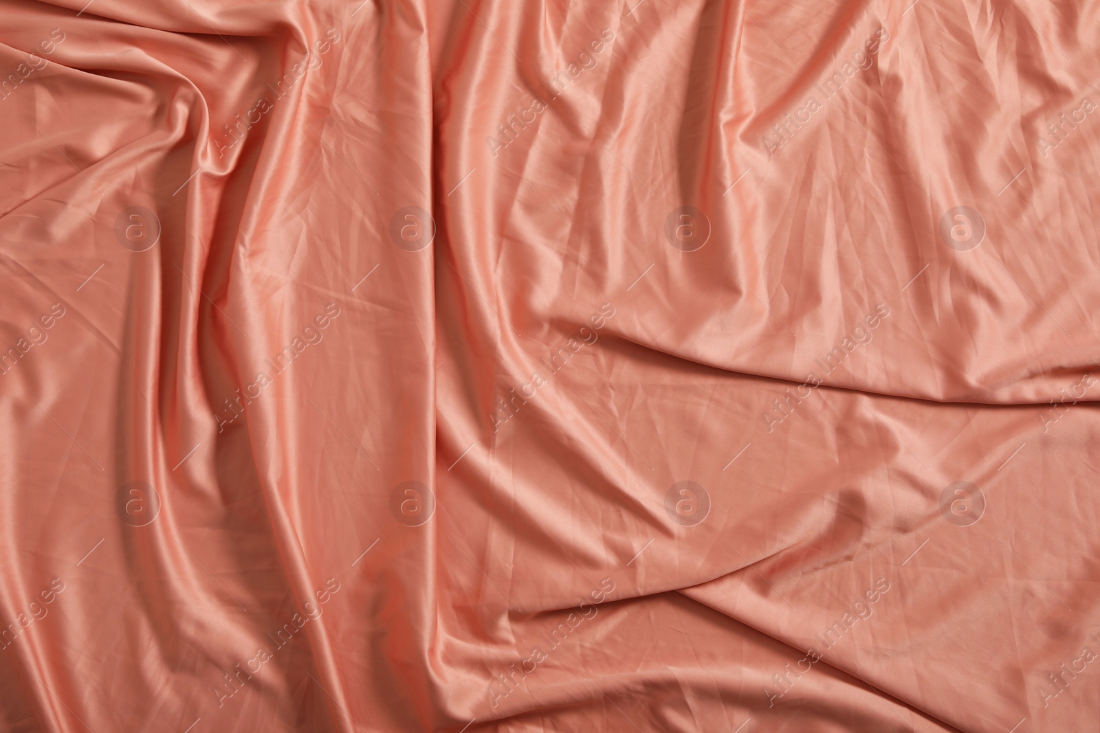 Photo of Crumpled coral fabric as background, top view