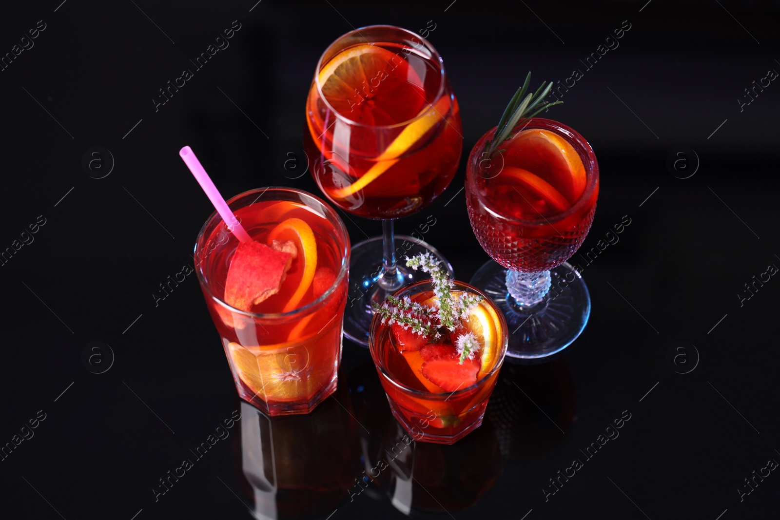 Photo of Many glasses of delicious refreshing sangria on black table