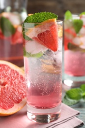 Photo of Delicious grapefruit lemonade with soda water and mint on blue wooden table, closeup. Fresh summer cocktail