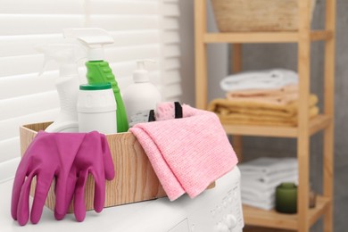 Different cleaning products in wooden box on washing machine indoors, space for text