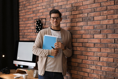 Journalist with notebook near brick wall in office