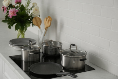 Photo of Saucepots and crepe pan on induction stove in kitchen