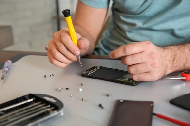 Photo of Technician repairing mobile phone at table, closeup