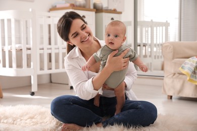 Photo of Happy young mother with her cute baby on floor at home