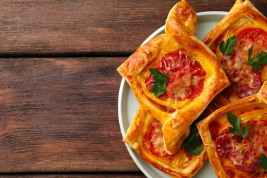 Photo of Fresh delicious puff pastry with cheese, tomatoes and parsley on wooden table, top view. Space for text