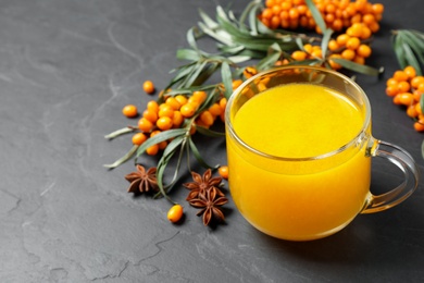 Photo of Sea buckthorn tea and fresh berries on grey table
