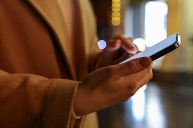 Photo of Woman using smartphone on night city street, closeup