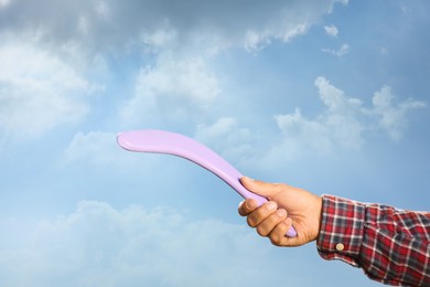Photo of Man throwing boomerang against blue sky, closeup