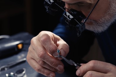 Photo of Professional jeweler working with ring on dark background, closeup
