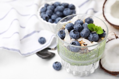 Photo of Tasty chia matcha pudding with coconut and blueberries on white table, space for text. Healthy breakfast