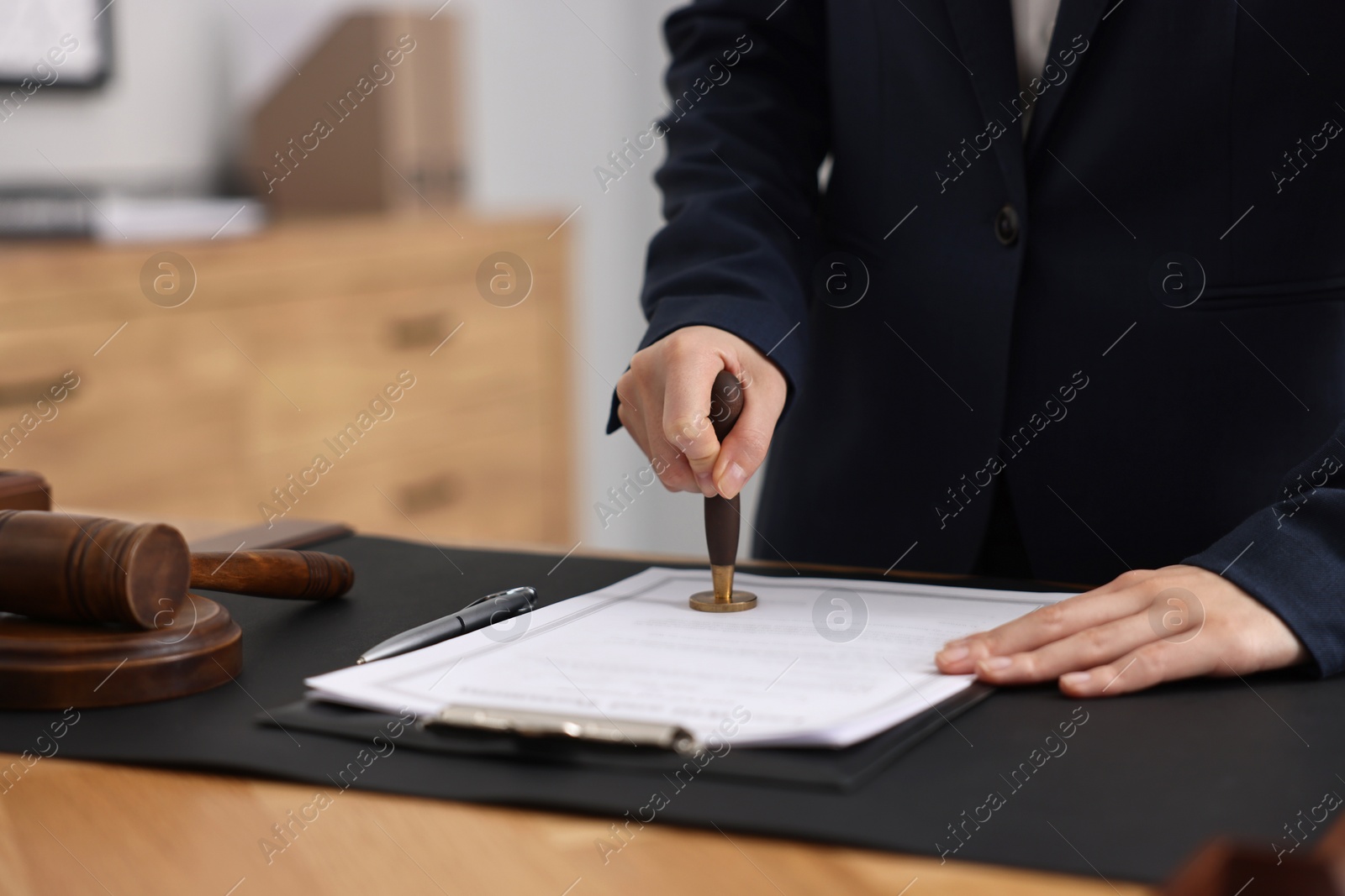 Photo of Notary sealing document at table in office, closeup