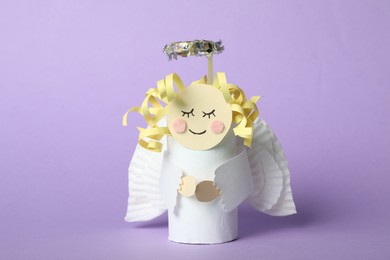 Photo of Toy angel made of toilet paper hub on lilac background