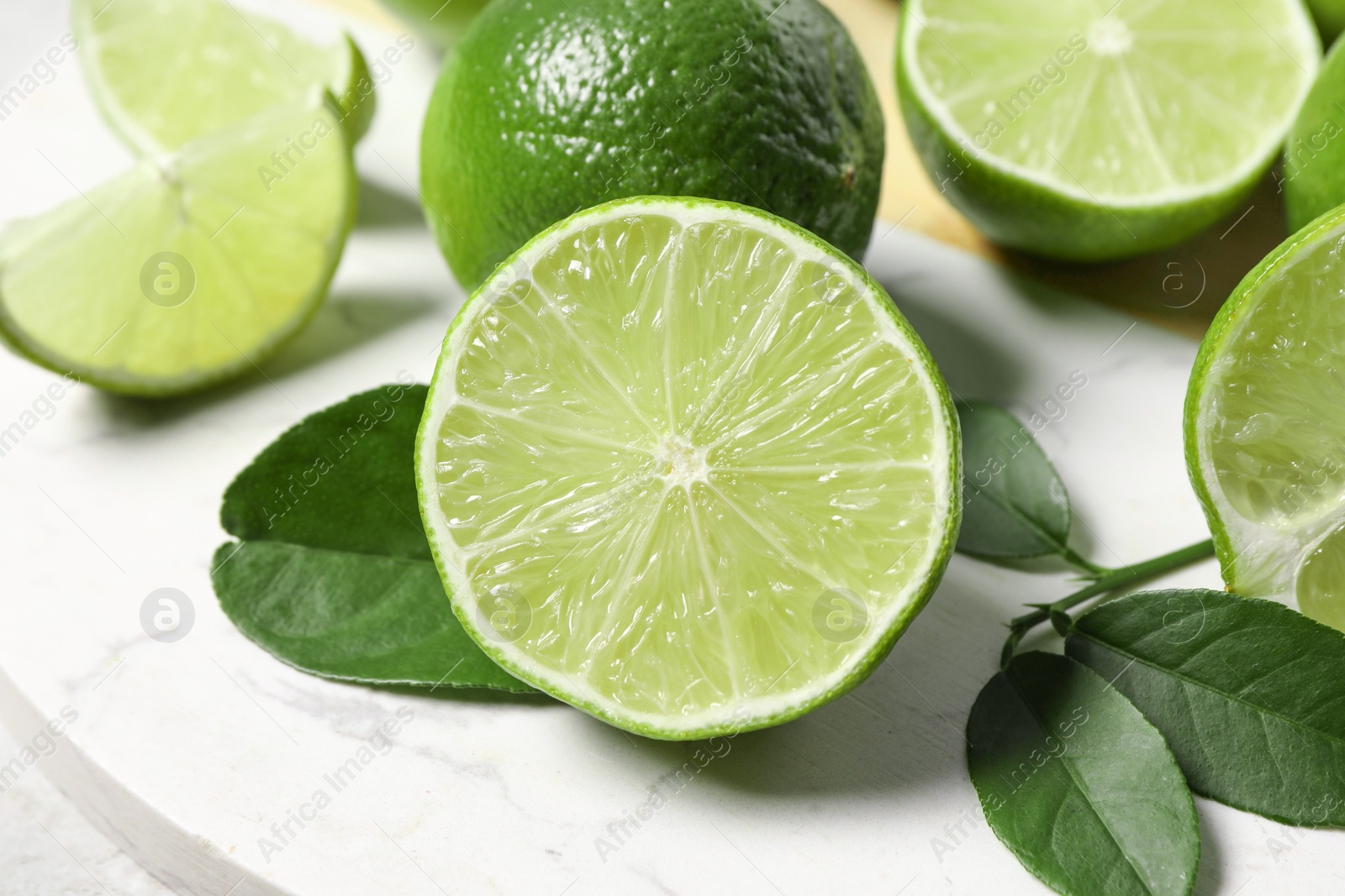 Photo of Fresh ripe limes and leaves on table, closeup