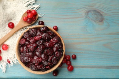 Tasty dried cranberries in bowl and fresh ones on light blue wooden table, top view. Space for text