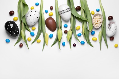 Photo of Flat lay composition with tulips, chocolate eggs and candies on white background, space for text. Easter celebration
