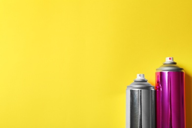 Photo of Cans of spray paint on color background, flat lay. Space for text