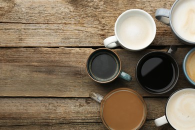 Photo of Different coffee drinks in cups on wooden table, flat lay. Space for text