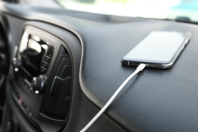 Photo of Smartphone with USB charging cable in modern car