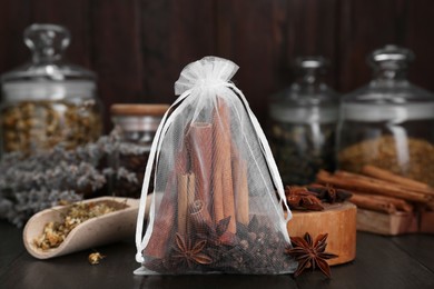 Photo of Scented sachet with cinnamon sticks and anise stars on wooden table