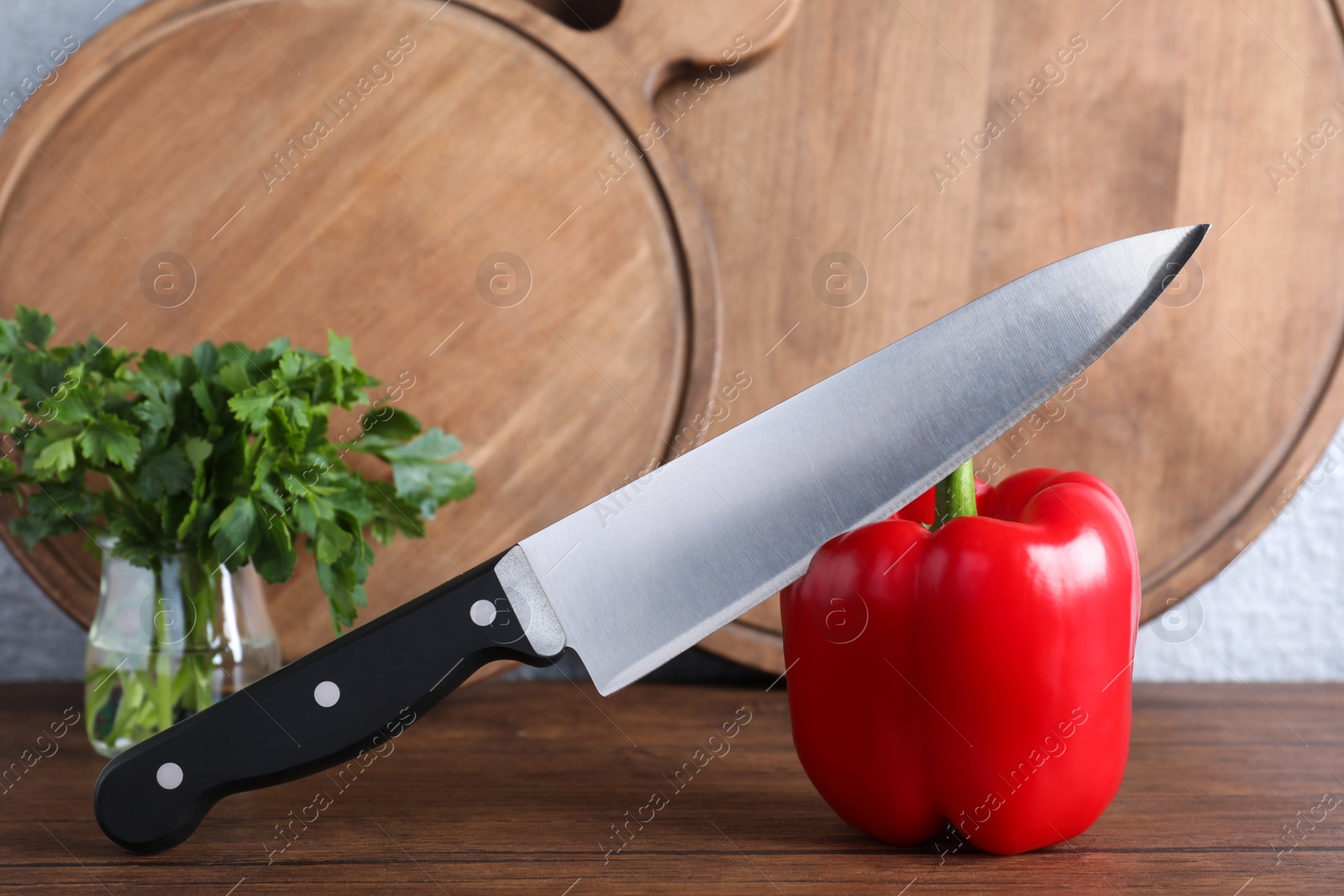Photo of Chef knife, bell pepper and serving boards on wooden table against grey background. Clean dishes