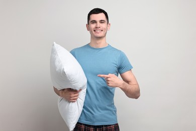 Photo of Happy man in pyjama holding pillow on light grey background