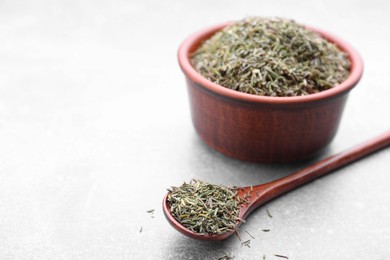 Photo of Bowl and spoon with dried thyme on grey table, closeup. Space for text