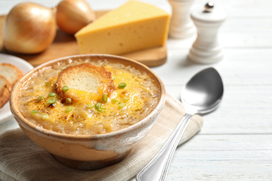 Photo of Tasty homemade french onion soup served on white wooden table