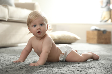 Photo of Cute little baby in diaper on carpet at home