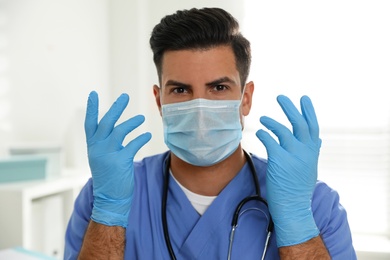 Photo of Doctor in protective mask and medical gloves against blurred background