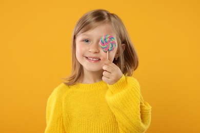 Photo of Portrait of happy girl with lollipop on orange background