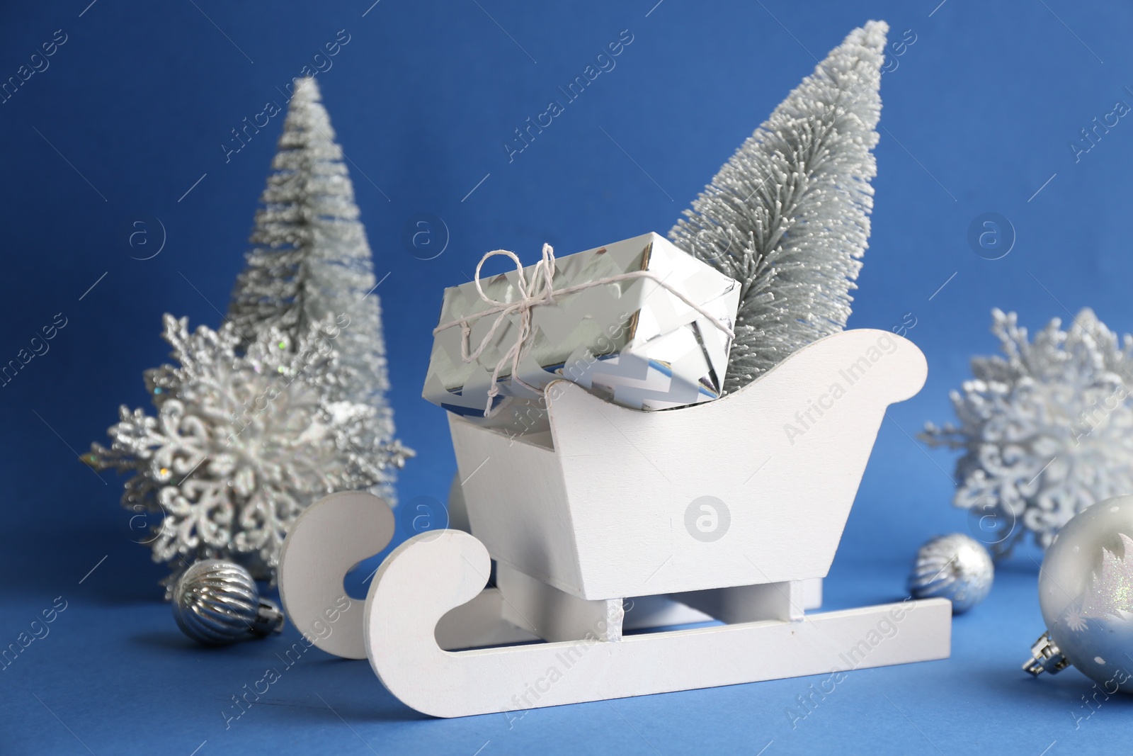 Photo of Beautiful Christmas composition with miniature sleigh on blue background