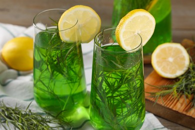 Photo of Glasses of refreshing tarragon drink with lemon slices on table