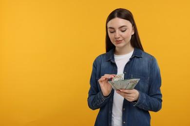 Photo of Woman with dollar banknotes on orange background, space for text