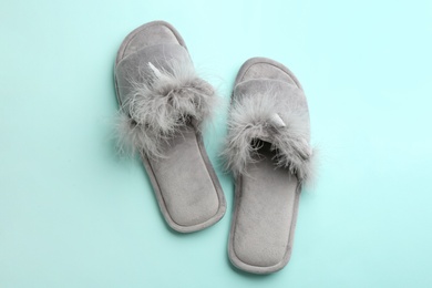 Pair of stylish soft slippers on turquoise background, flat lay