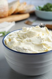 Photo of Bowl of tasty cream cheese on grey table, closeup