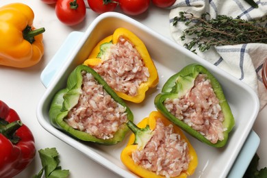 Photo of Raw stuffed peppers and ingredients on white table, flat lay