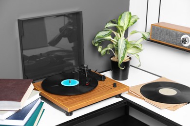 Photo of Stylish turntable with vinyl disc near grey wall in room