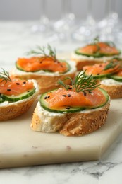 Photo of Tasty canapes with salmon, cucumber and cream cheese on white marble table, closeup