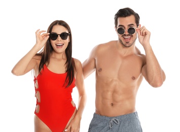 Photo of Young attractive couple in beachwear and sunglasses on white background