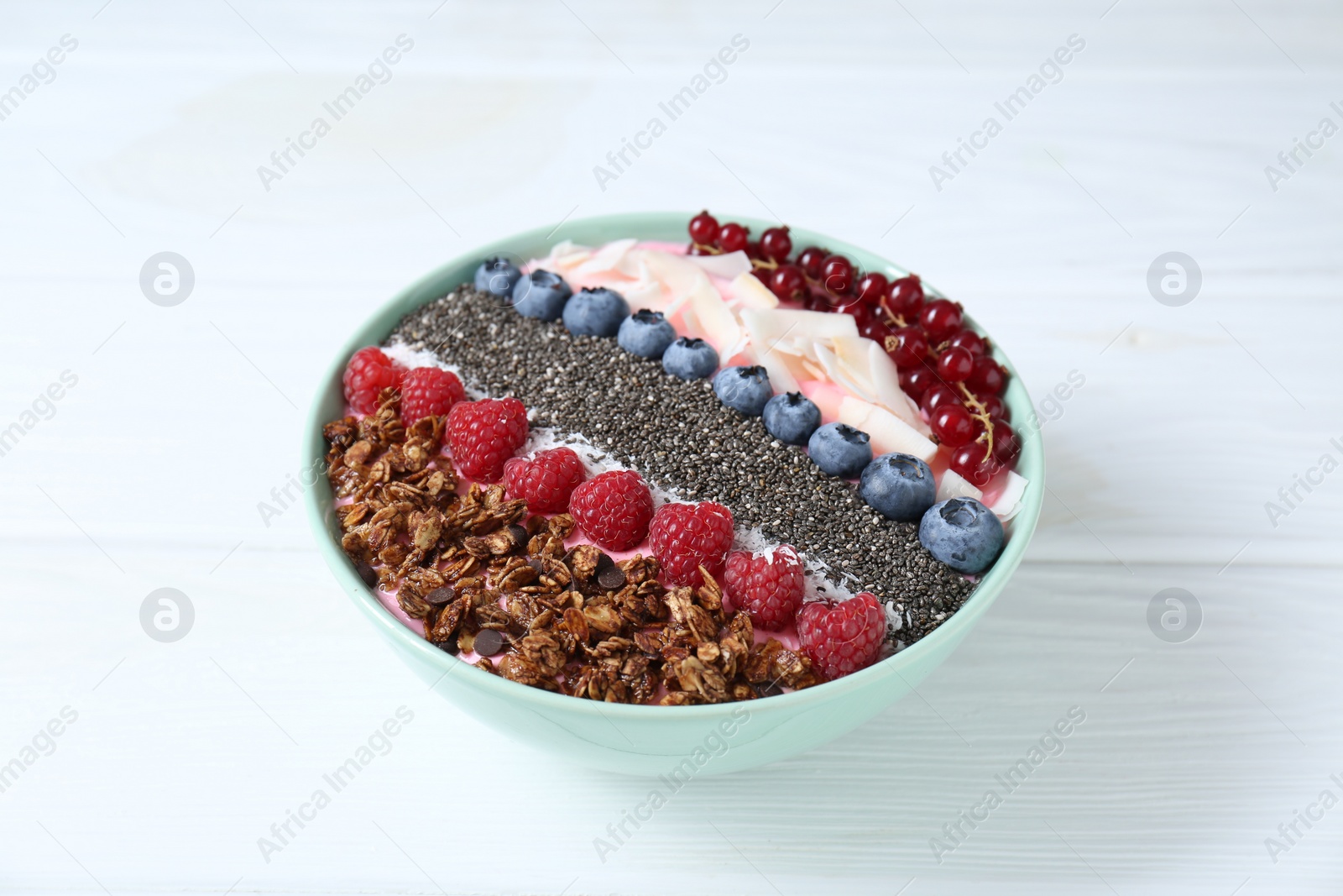 Photo of Tasty smoothie bowl with fresh berries and granola on white table