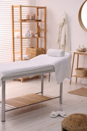 Photo of Comfortable massage table with clean towels in spa center