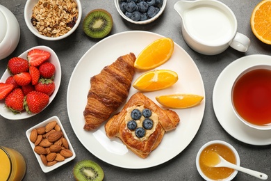 Photo of Delicious pastries and orange slices on grey table, flat lay. Buffet service