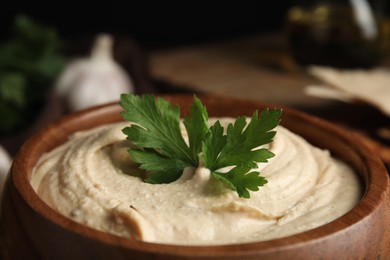 Photo of Delicious creamy hummus with parsley in bowl, closeup