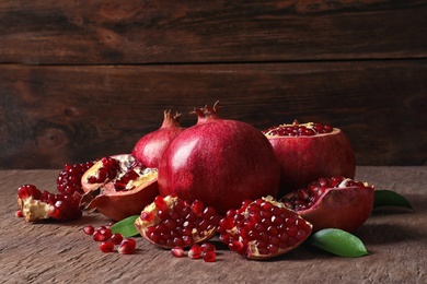 Photo of Composition with ripe pomegranates and leaves on table. Space for text