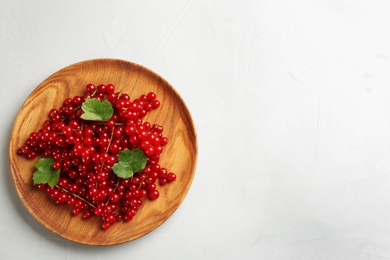 Photo of Delicious red currants and leaves on light table, top view. Space for text