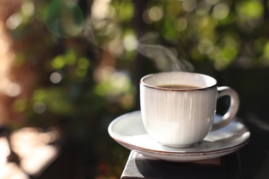 Photo of Cup of hot aromatic coffee on table in outdoor cafe. Space for text