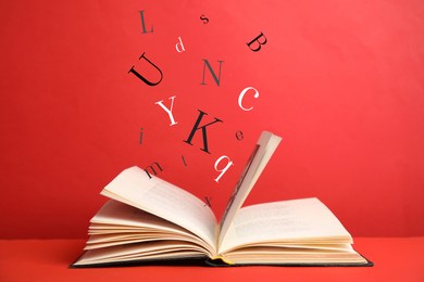 Image of Open book with letters flying out of it on red background