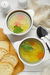 Photo of Delicious bouillon served on white wooden table, flat lay
