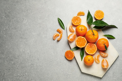 Photo of Fresh ripe tangerines and space for text on grey table, flat lay. Citrus fruit